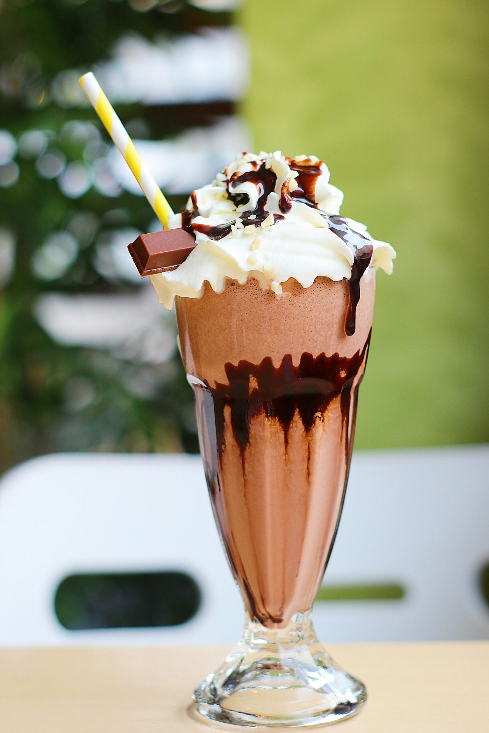 Indulgent chocolate milkshake topped with whipped cream and a straw, perfect for dessert cravings.