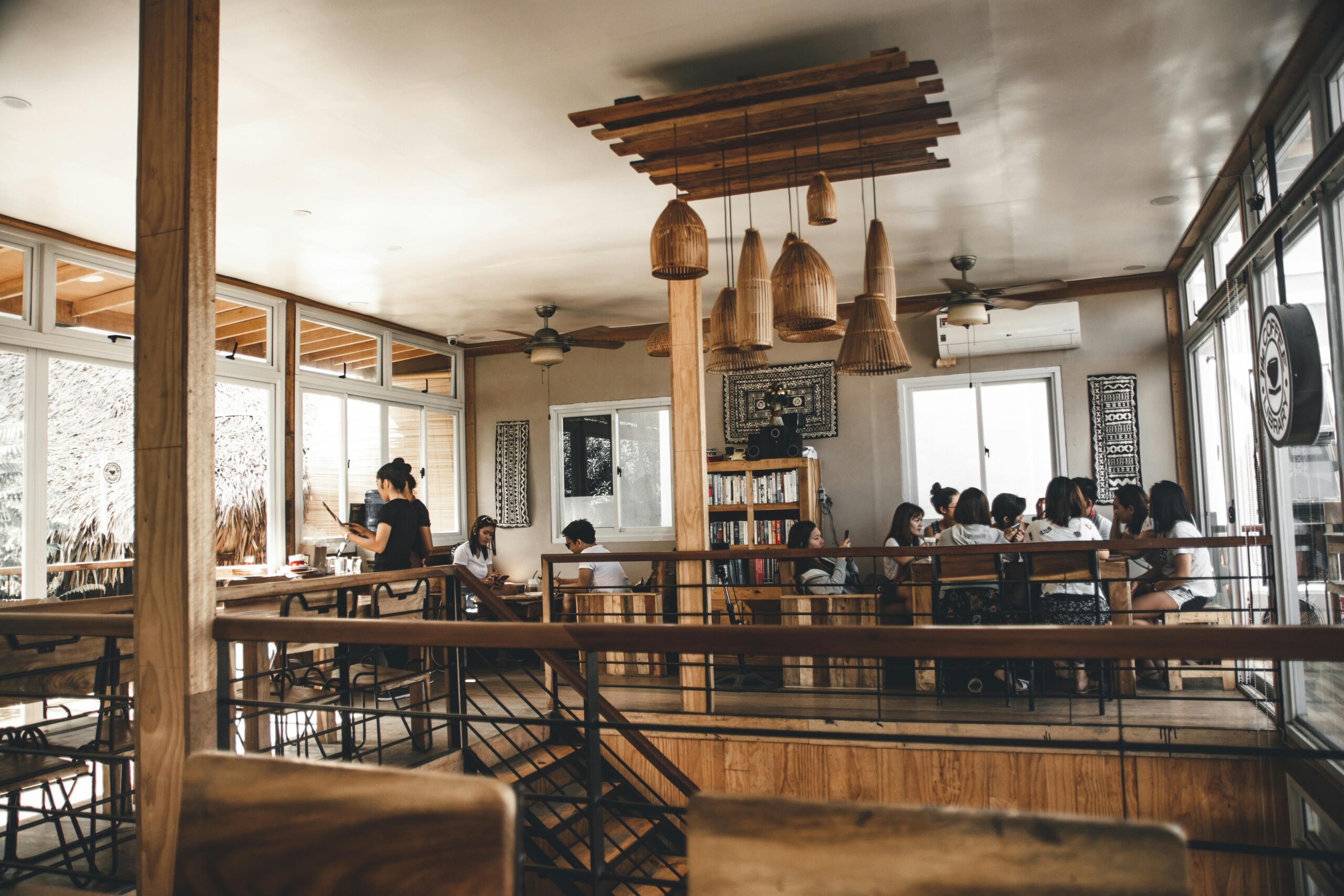 A modern café interior featuring a group dining, wooden decor, and natural lighting.