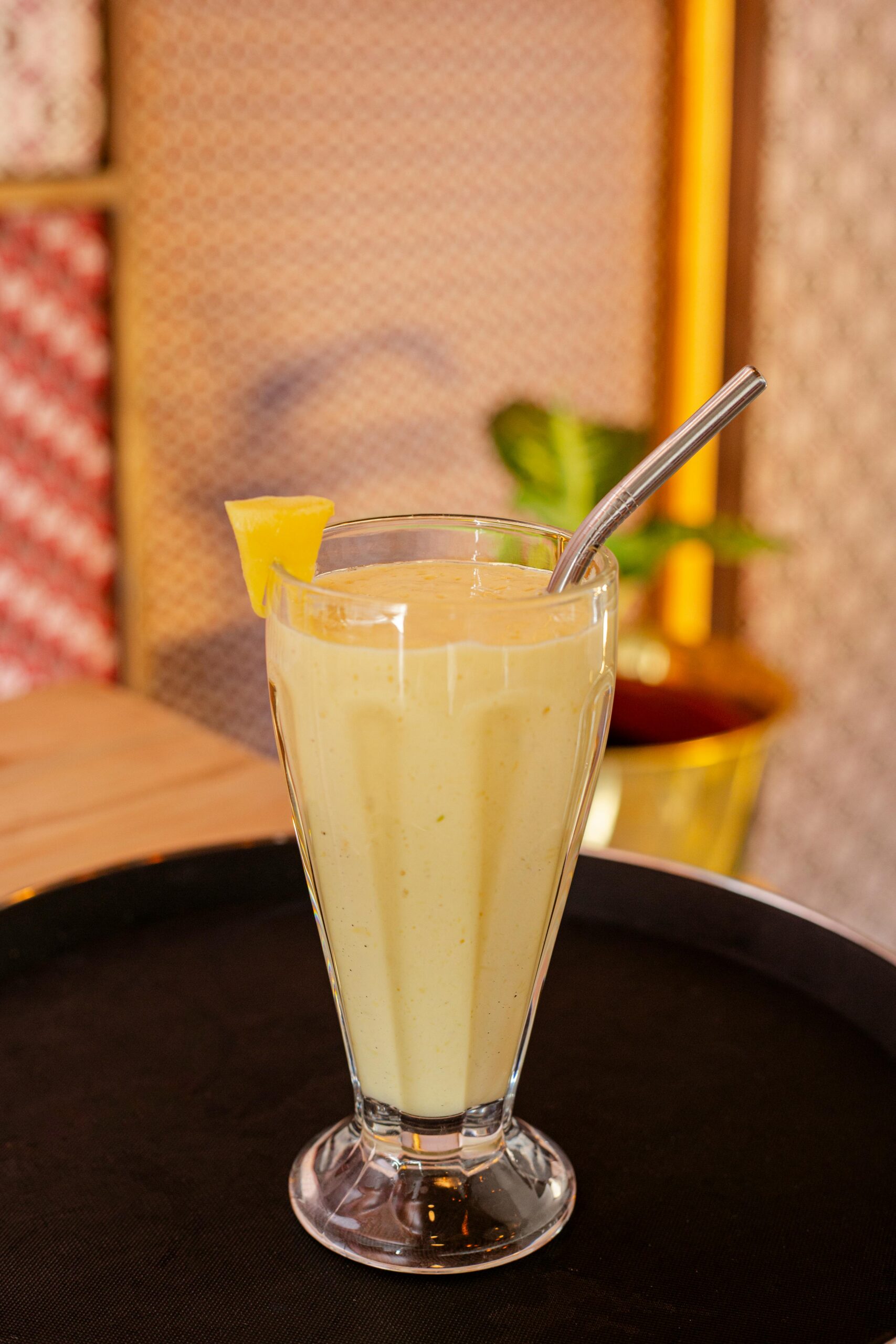 Refreshing mango smoothie served in a tall glass with a steel straw, topped with a pineapple slice.